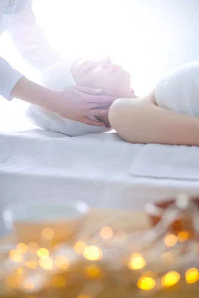 Mujer joven acostada en una mesa de masaje, relajándose con los ojos cerrados. Una mujer. Salón de spa —  Fotos de Stock