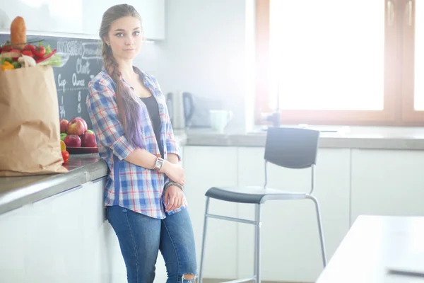 Retrato de mujer joven de pie con los brazos cruzados contra el fondo de la cocina. —  Fotos de Stock