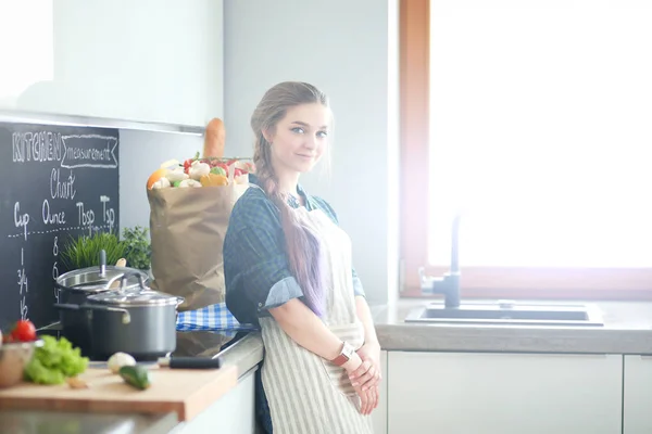 Junge Frau steht am Herd in der Küche . — Stockfoto