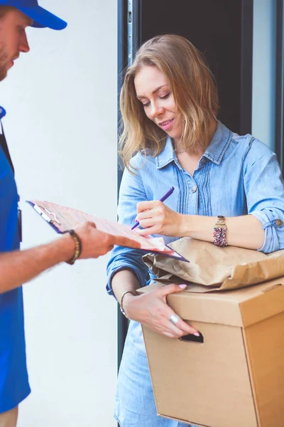 Repartidor sonriente con uniforme azul que entrega la caja de paquetes al destinatario: concepto de servicio de mensajería. Repartidor sonriente en uniforme azul — Foto de Stock