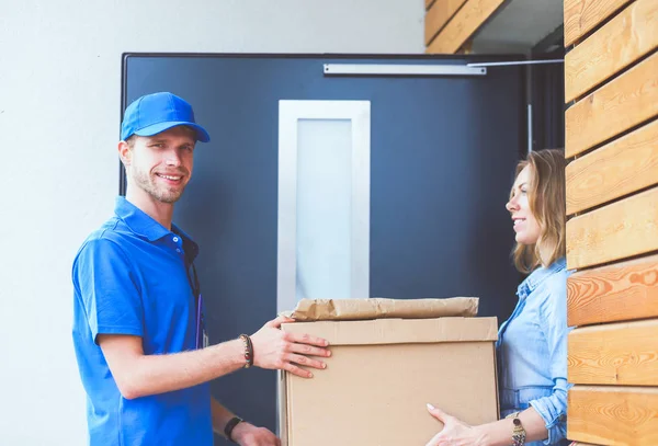 Mavi üniformalı gülümseyen kurye servis konseptine paket kutusu teslim eden teslimatçı. Mavi üniformalı gülümseyen teslimatçı.
