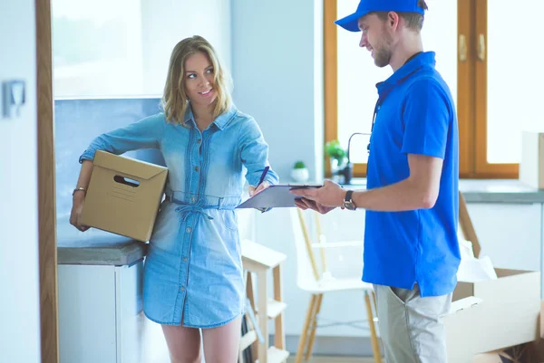 Mavi üniformalı gülümseyen kurye servis konseptine paket kutusu teslim eden teslimatçı. Mavi üniformalı gülümseyen teslimatçı.