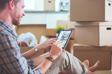 Genç bir çift yeni ev içinde hareket. Oturma ve açma sonra rahatlatıcı. Bir şey üstünde laptop arıyorum. Genç Çift