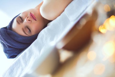 Masaj masasında uzanmış gözleri kapalı rahatlayan genç bir kadın. - Kadın. Spa salonu