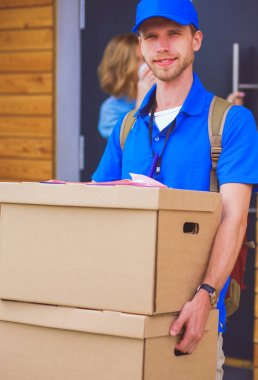 Mavi üniformalı gülümseyen kurye servis konseptine paket kutusu teslim eden teslimatçı. Mavi üniformalı gülümseyen teslimatçı.