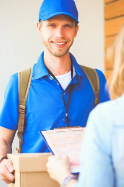 Mavi üniformalı gülümseyen kurye servis konseptine paket kutusu teslim eden teslimatçı. Mavi üniformalı gülümseyen teslimatçı.