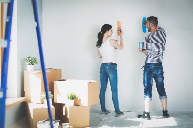 Yeni evin içini boyayan mutlu, genç bir çiftin portresi. Genç çift