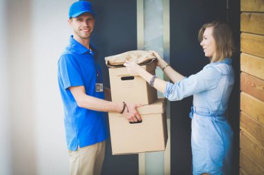 Mavi üniformalı gülümseyen kurye servis konseptine paket kutusu teslim eden teslimatçı. Mavi üniformalı gülümseyen teslimatçı.