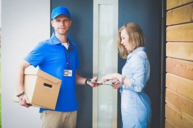 Mavi üniformalı gülümseyen kurye servis konseptine paket kutusu teslim eden teslimatçı. Mavi üniformalı gülümseyen teslimatçı.