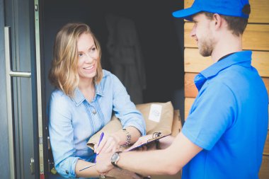 Mavi üniformalı gülümseyen kurye servis konseptine paket kutusu teslim eden teslimatçı. Mavi üniformalı gülümseyen teslimatçı.
