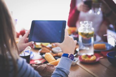 Ahşap masada otururken birlikte yemek yiyen bir grup insanın üst düzey görüntüsü. Masada yemek var. İnsanlar fast food yiyor..