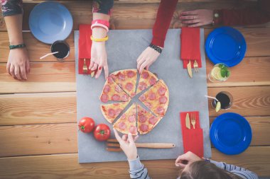 Ahşap masada otururken birlikte yemek yiyen bir grup insanın üst düzey görüntüsü. Masada yemek var. İnsanlar fast food yiyor..