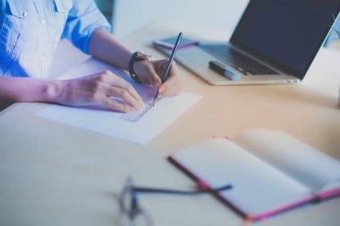 Ofis masasında dizüstü bilgisayarla oturan genç bir kadın. Genç bir kadın. Dizüstü bilgisayar