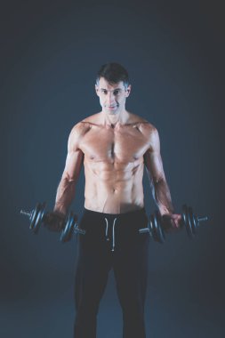 Yakışıklı kaslı adam dumbell ile çalışma dışarı. Kişisel fitness eğitmeni. Kişisel eğitim.