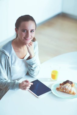 Mutfakta portakal suyu ve tableti olan genç bir kadın..