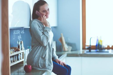 modern mutfakta otururken cep telefonu kullanan kadın.