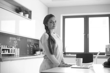 Cep telefonu ayakta modern mutfak kullanan kadın.