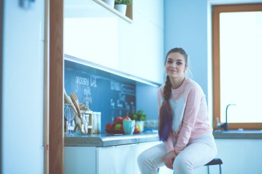 Mutfakta masada oturan genç kadın.