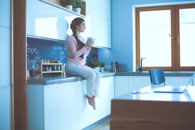 Mutfakta masada oturan genç kadın.