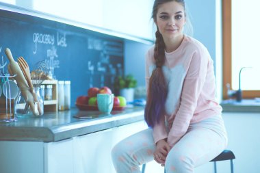 Mutfakta masada oturan genç kadın.