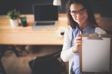 Masanın yanında dizüstü bilgisayarı ve bir fincan kahveyle duran genç bir kadın. İş yeri. İş Kadını.