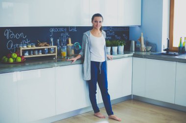 Mutfakta portakal suyu ve tableti olan genç bir kadın..