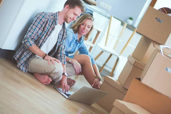 Genç bir çift yeni ev içinde hareket. Oturma ve açma sonra rahatlatıcı. Bir şey üstünde laptop arıyorum. Genç Çift