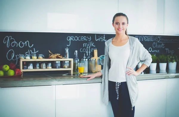 Mujer joven con jugo de naranja y tableta en la cocina. —  Fotos de Stock