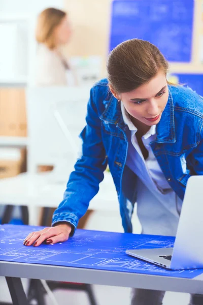 Masanın yanında duran iki genç kadın enstrüman, plan ve dizüstü bilgisayarla.