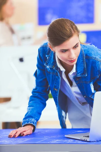 Masanın yanında duran iki genç kadın enstrüman, plan ve dizüstü bilgisayarla.