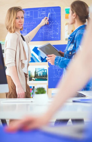 Twee jonge vrouw in de buurt van bureau met instrumenten, plan en laptop. — Stockfoto