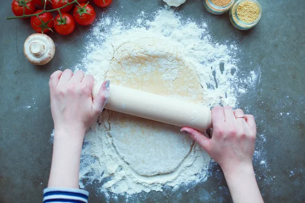 Güzel bir kadın mutfakta pasta pişiriyor. Masanın yanında duruyor..