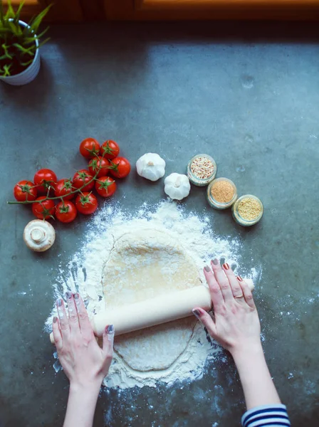 Güzel bir kadın mutfakta pasta pişiriyor. Masanın yanında duruyor..