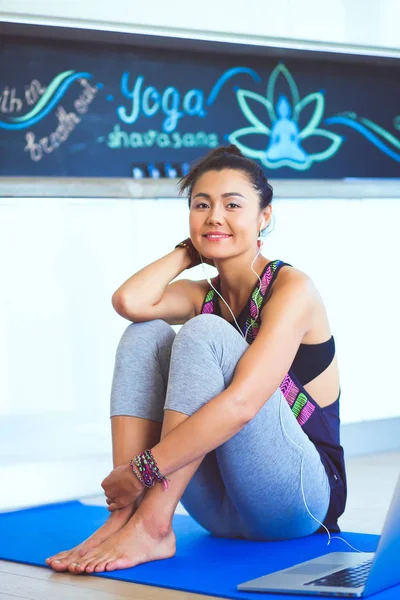 Portrait of smiling yoga woman sitting at yoga mat after workout at yoga studio. Yoga. Woman.