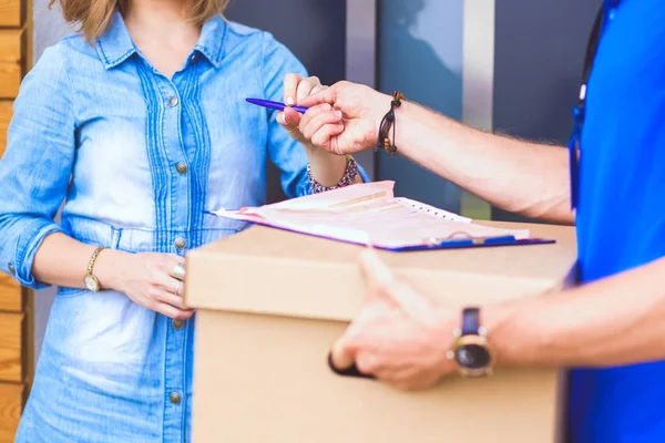 Mavi üniformalı gülümseyen kurye servis konseptine paket kutusu teslim eden teslimatçı. Mavi üniformalı gülümseyen teslimatçı.