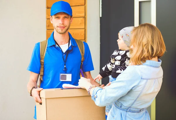 Mavi üniformalı gülümseyen kurye servis konseptine paket kutusu teslim eden teslimatçı. Mavi üniformalı gülümseyen teslimatçı.
