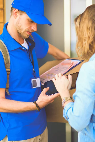 Mavi üniformalı gülümseyen kurye servis konseptine paket kutusu teslim eden teslimatçı. Mavi üniformalı gülümseyen teslimatçı.