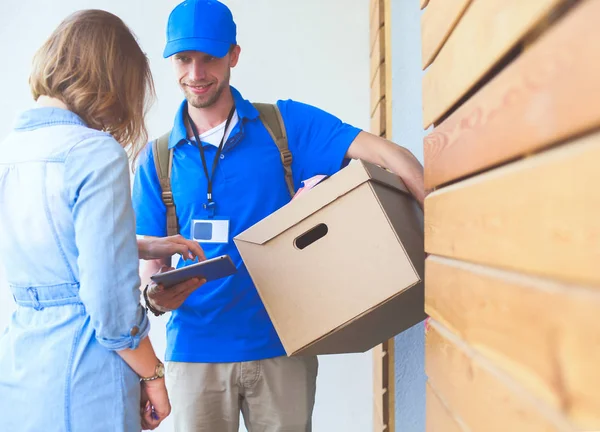 Mavi üniformalı gülümseyen kurye servis konseptine paket kutusu teslim eden teslimatçı. Mavi üniformalı gülümseyen teslimatçı.