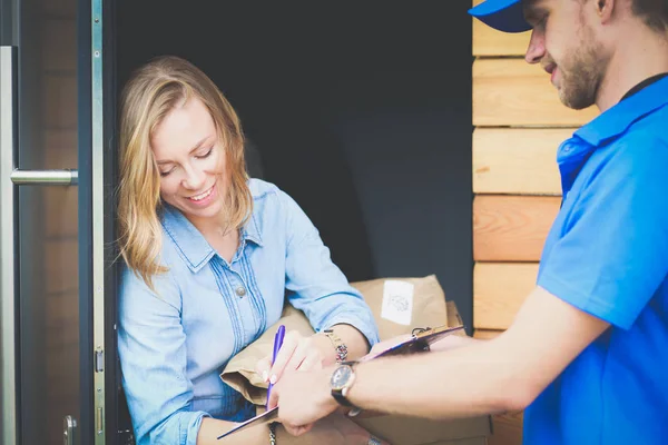 Mavi üniformalı gülümseyen kurye servis konseptine paket kutusu teslim eden teslimatçı. Mavi üniformalı gülümseyen teslimatçı.