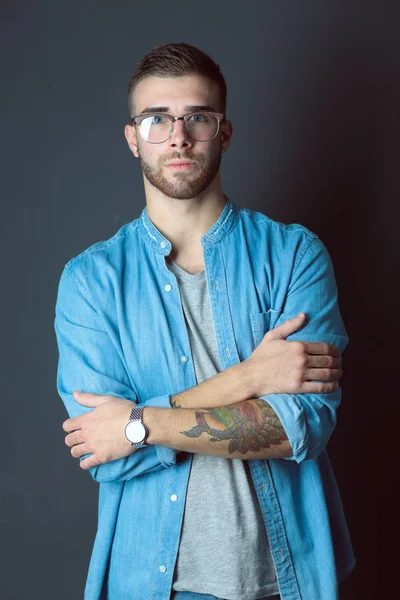 Mutlu bir casual adam ayakta karanlık bir arka plan üzerinde izole portresi. Yakışıklı erkek poz.