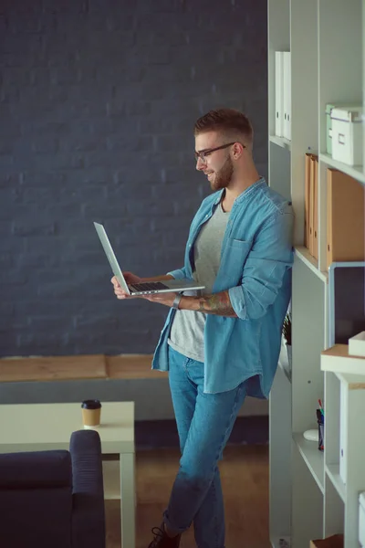 Jongeman houdt laptop staan in de buurt muur. — Stockfoto