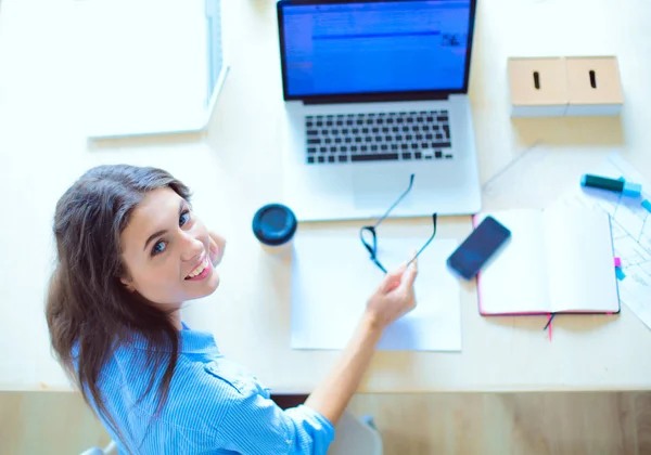 Ofis masasında oturan genç bir kadın dizüstü bilgisayar ekranına bakıyor. Genç kadın.