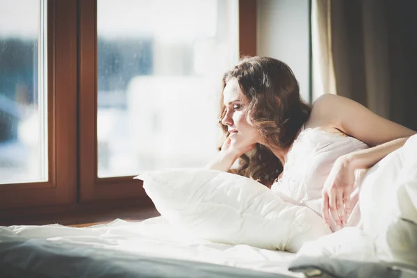 Pencere yakınındaki erken sabah yatakta yatan kadın. — Stok fotoğraf