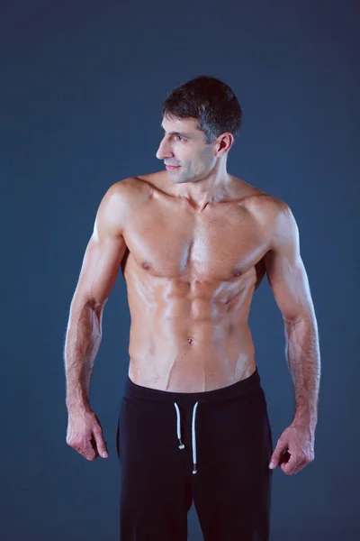 Muscular man. Muscular man on a grey background showing muscles. Fitness instructor. Fitness professional. Workout. Mens fitness. — Stock Photo, Image