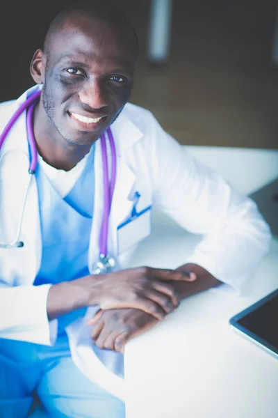 Портрет молодого чоловіка-лікаря, який носить гарнітуру під час використання комп'ютера за столом у клініці. Лікар . — стокове фото