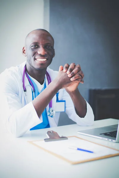 Retrato de un joven médico con auriculares mientras usa la computadora en el escritorio de la clínica. Doctor.. — Foto de Stock