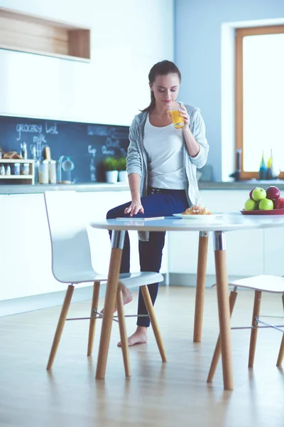 Молодая женщина с апельсиновым соком и таблетками на кухне. — стоковое фото