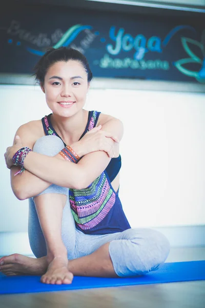 Portræt af den smilende yogakvinde, der sidder på yogamåtten efter træning i yoga studiet. Yoga. Kvinde . - Stock-foto