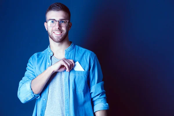 Joven sosteniendo una tarjeta de crédito de pie sobre fondo gris. Joven empresario. — Foto de Stock