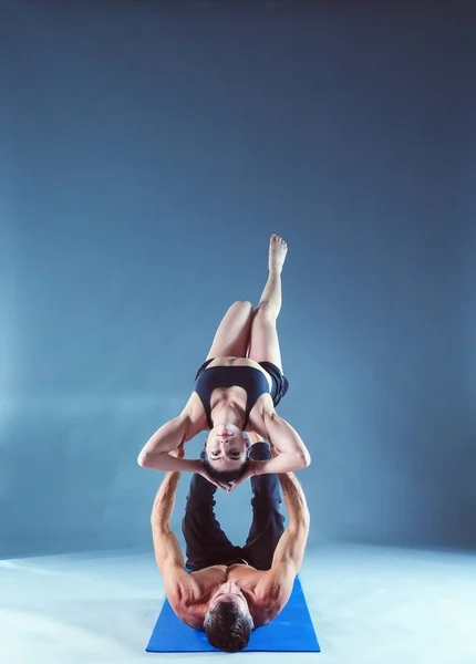 Young couple practicing acro yoga on mat in studio together. Acroyoga. Couple yoga. Partner yoga.